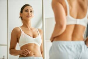 Woman in mirror looking at breast recostruction results in Mesa, AZ